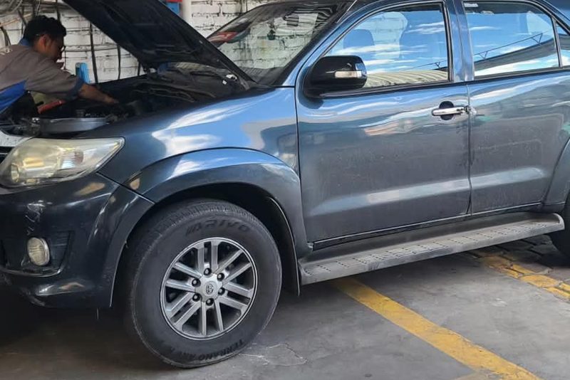 Vehículo con el capó abierto en el taller mientras un técnico le hace el mantenimiento