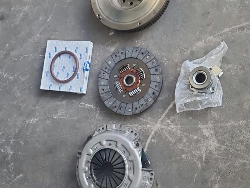 Kit de embrague completo sobre el piso del taller: volante, disco, prensa y collarín